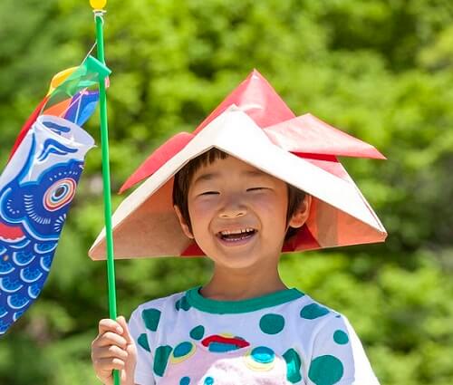 a kid putting on paper craft samurai helmet