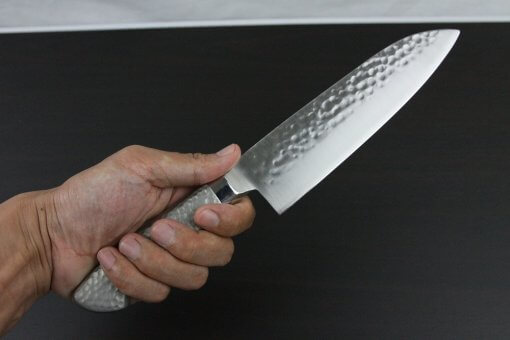 Japanese Chef Knife, Hammer Finish Series, Santoku multi-purpose knife 180mm left-handed, grabbed by a man's hand