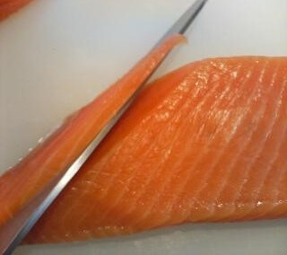 cut salmon sashimi by a sushi knife