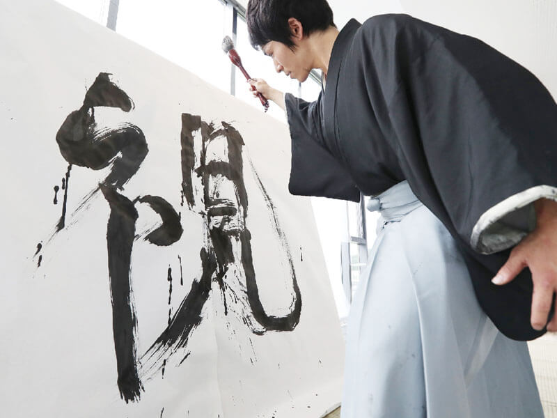 a calligrapher writing his art on large paper