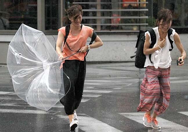 women blew by wind of typhoon across a street